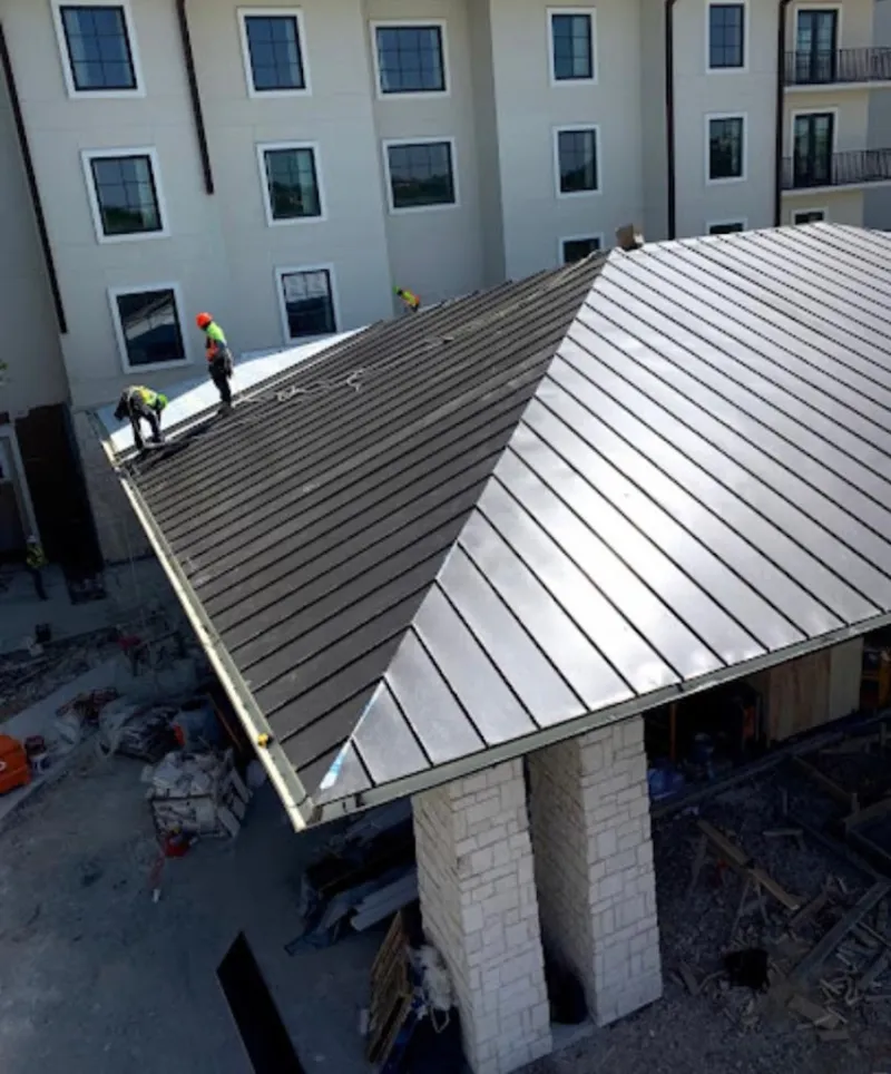 Crew installing standing seam metal roof panels on a commercial project in Sylvania